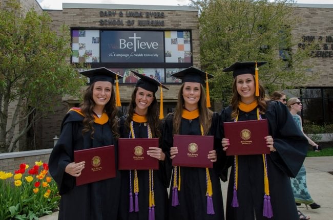 Walsh Graduates holding their degrees