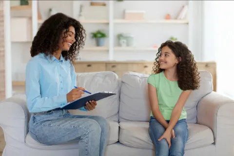 A school counselor making a young child smile during a session