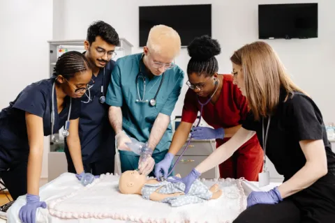 A nursing instructor showing students how to perform CPR on an infant